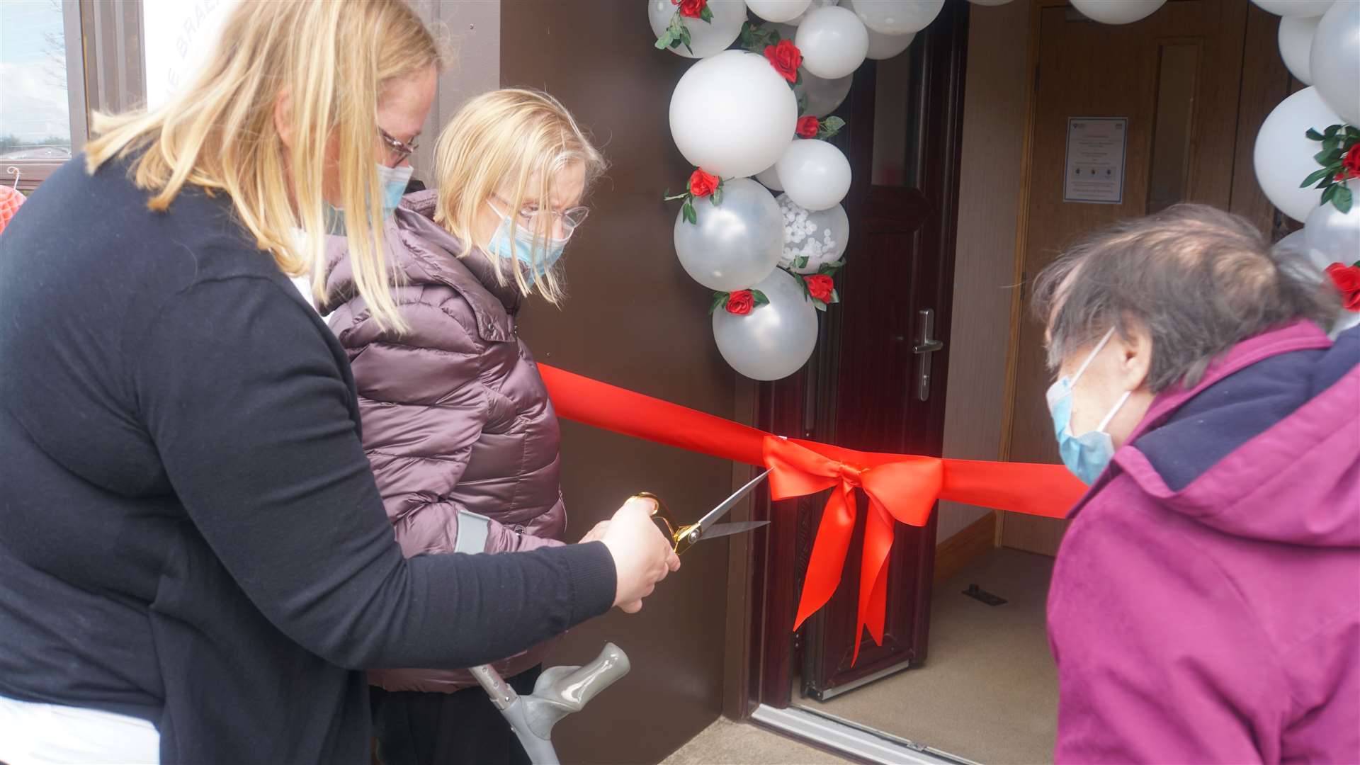 Laurandy's manager Tracy Mackay holds the scissors for the ribbon cutting moment as service users Mary Inkster, left and Wilma Donaldson prepare to enter the centre again.