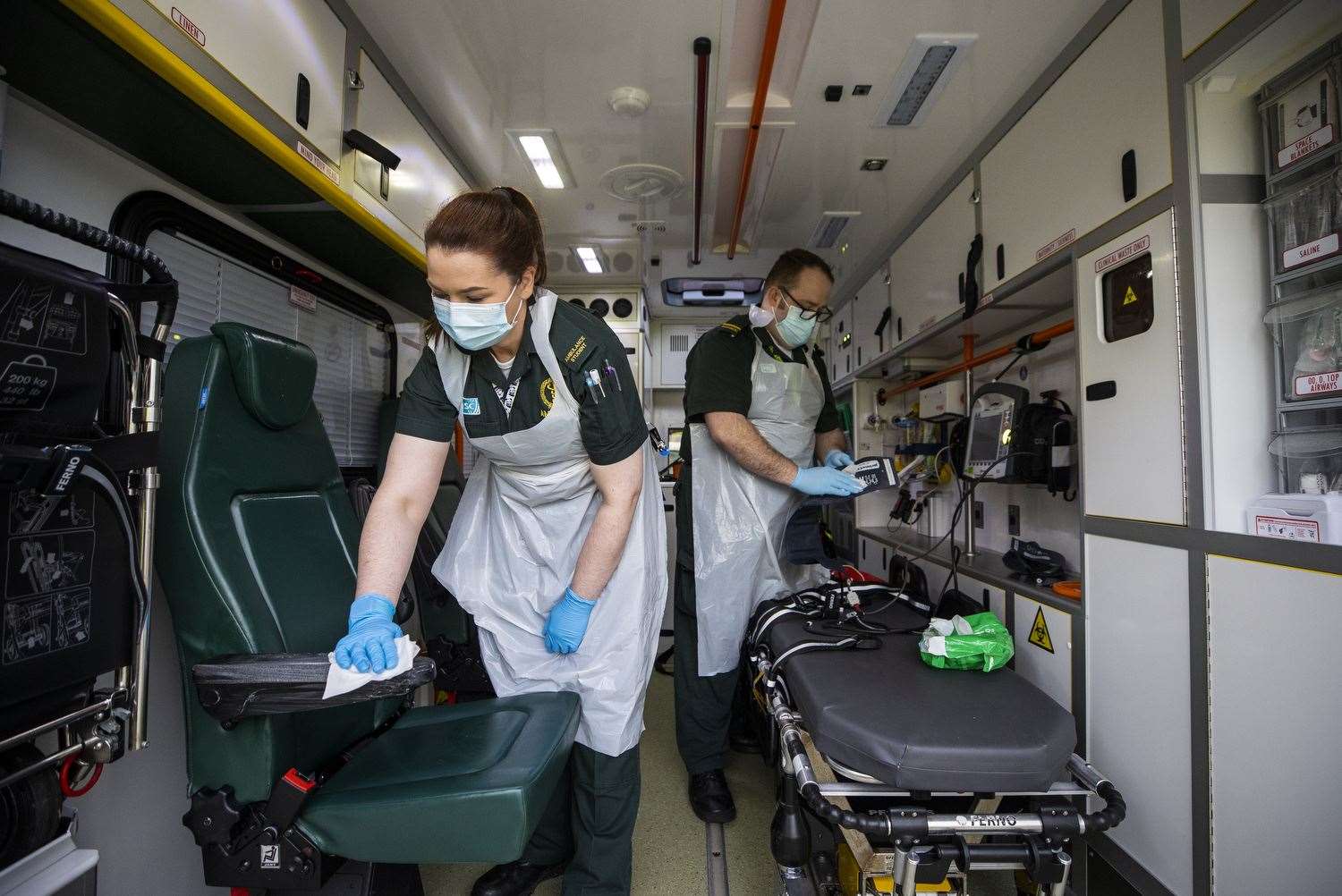 Ruth Corscadden and Daniel McCollam cleaning the ambulance after bringing a patient to the Causeway Hospital (Liam McBurney/PA)