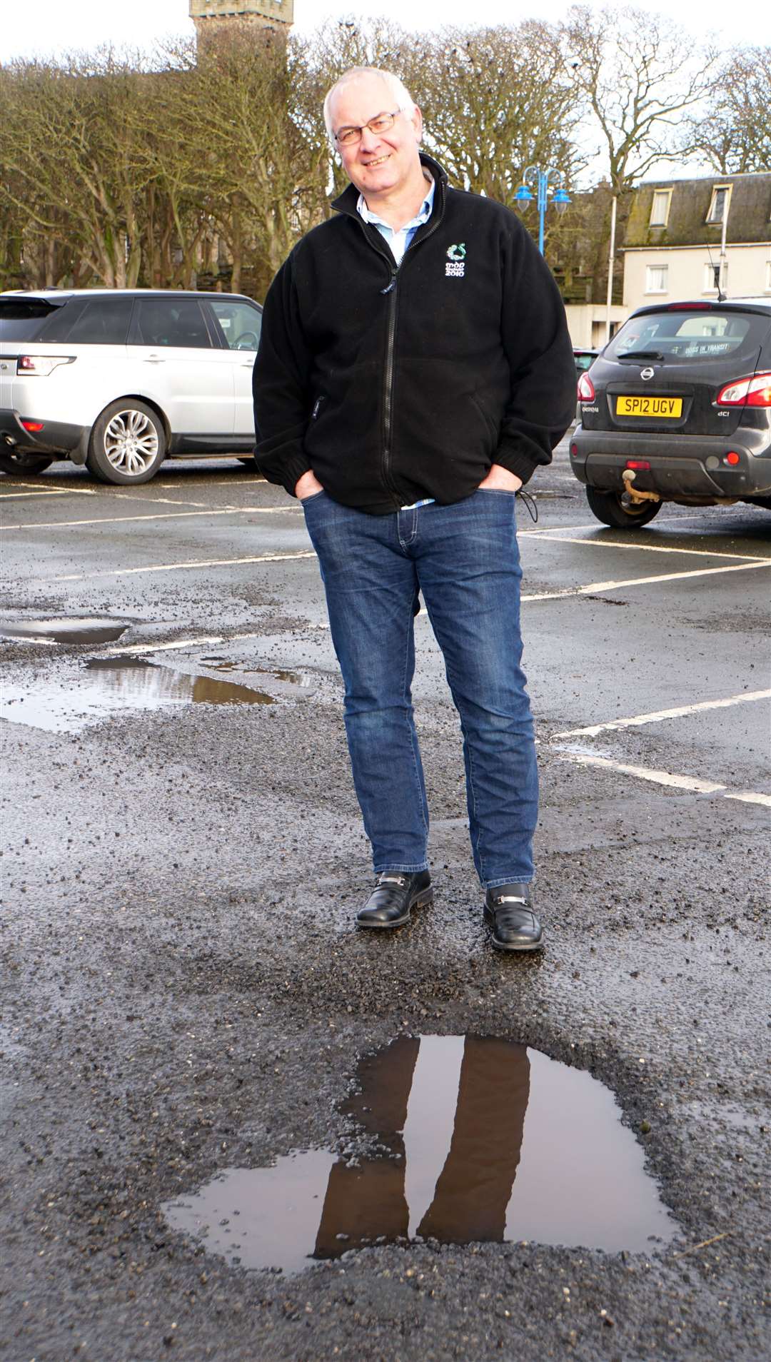 Councillor Bremner pictured last year beside one of the many potholes that drivers had to negotiate around in the badly pockmarked car park. Picture: DGS