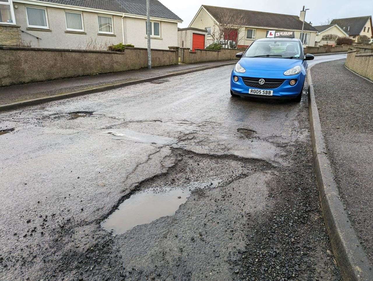 Ross Bain's car beside a damaged section of road in the Lindsay Drive area.