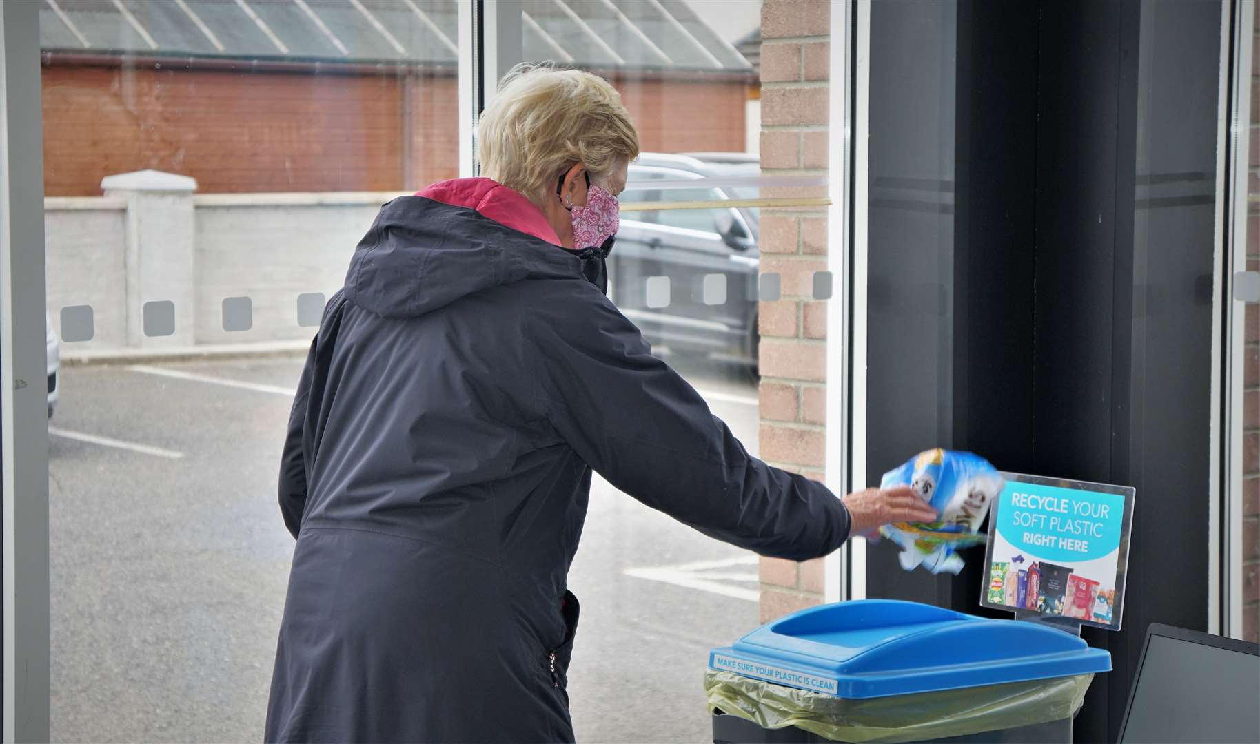 A local customer deposits a soft plastic wrapper in the new bin.