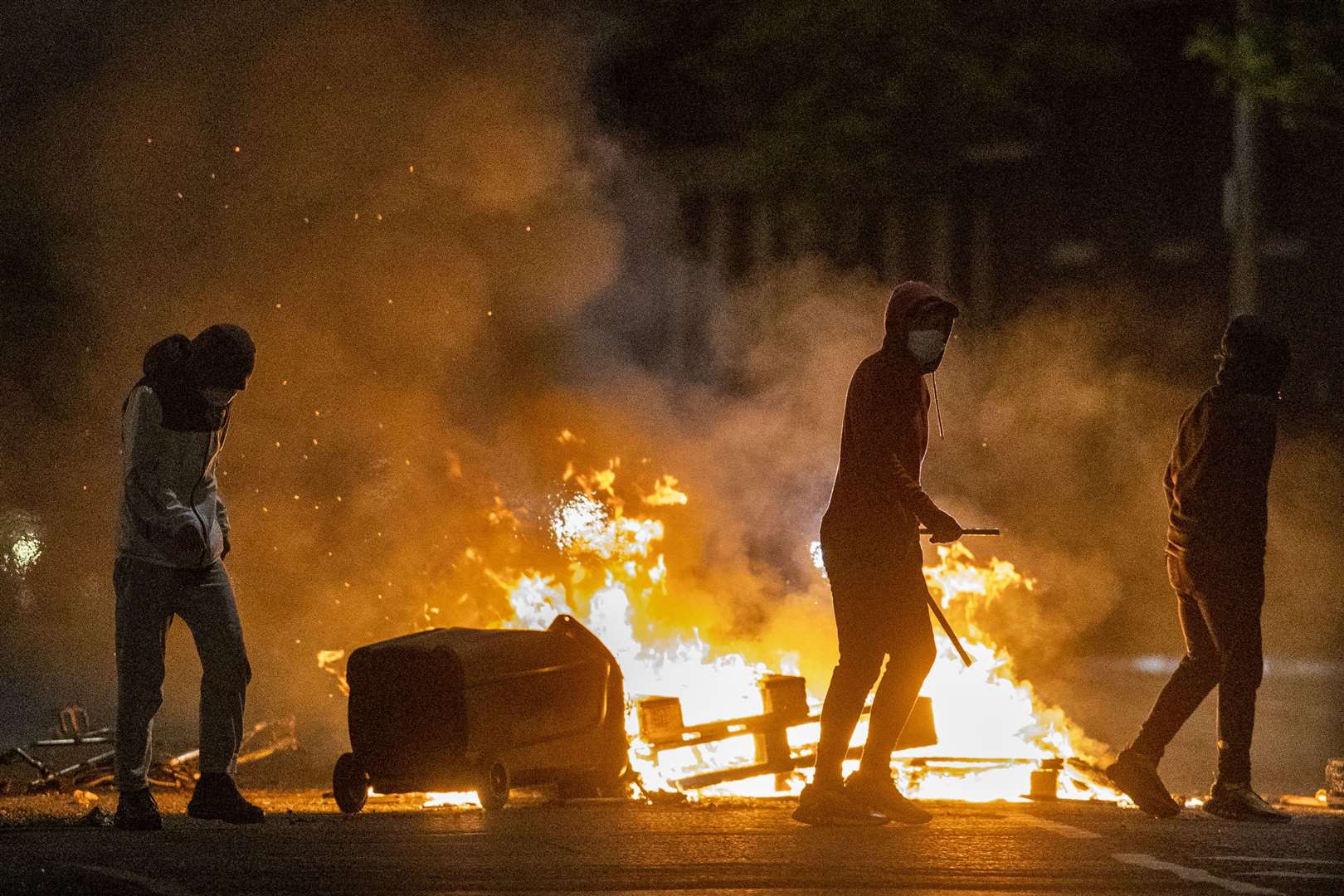 People stand next to a fire in a street in Belfast on Wednesday night (Liam McBurney/PA)