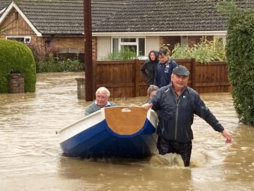 Simon O’Brien (right) used his homemade boat which he built for his grandchildren to rescue elderly residents from their home in the village of Debenham, Suffolk, where people were cut off by flood water on Friday (PA/Mary Scott)