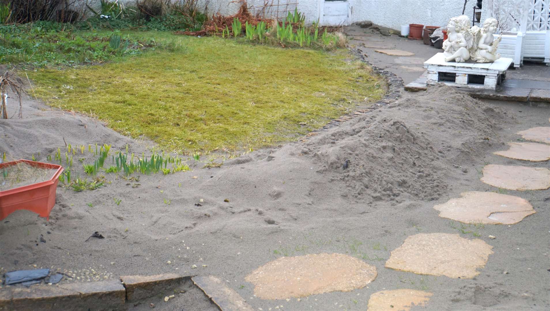 Sand shovelled into piles in a garden.