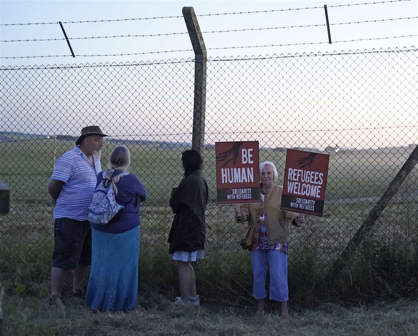 Protesters at the perimeter of MoD Boscombe Down, near Salisbury, where a Boeing 767 aircraft was believed to due to take asylum seekers to Rwanda (Andrew Matthews/PA)